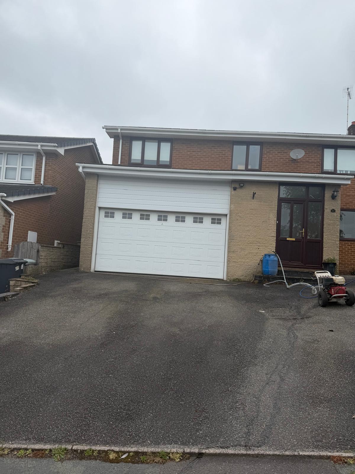 Driveway cleaning in progress with pressure washer equipment set up outside UK home