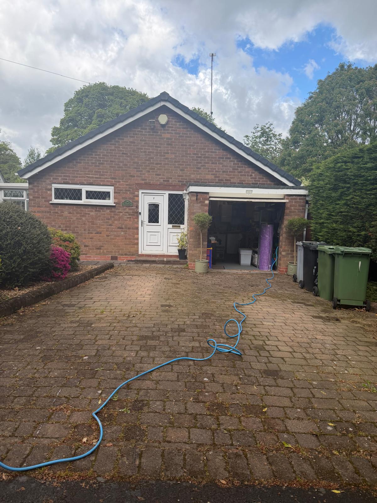 Block paving driveway before pressure washing - dirty bungalow frontage with hose laid out