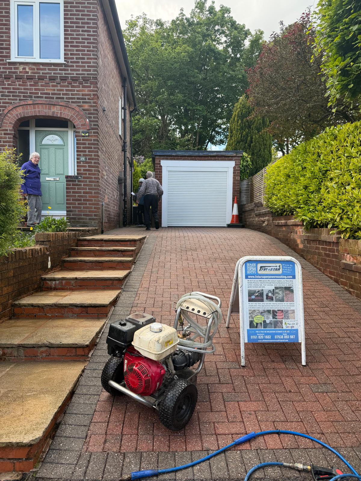 Herringbone block paving driveway after cleaning - vibrant colour restored with equipment on site