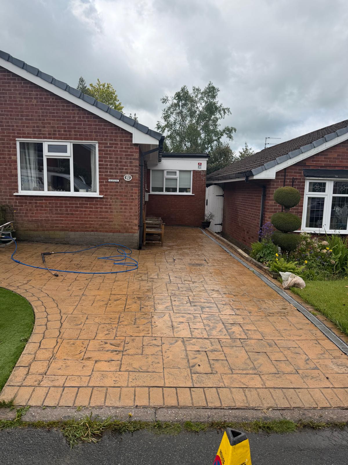 Pattern imprinted concrete bungalow driveway after pressure washing - warm sandstone colour restored
