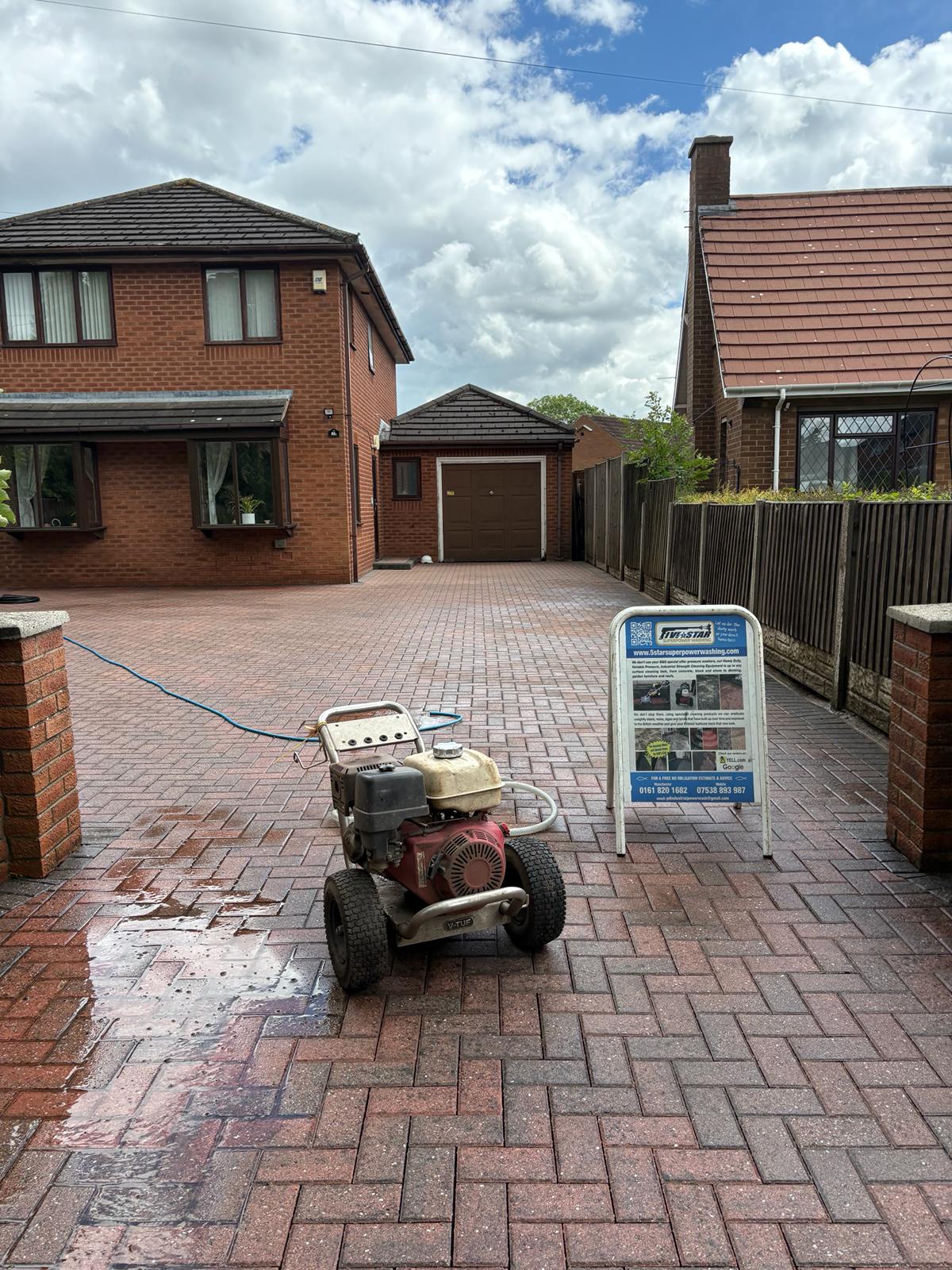 Clean block paving driveway with pressure washing equipment and company sign on display